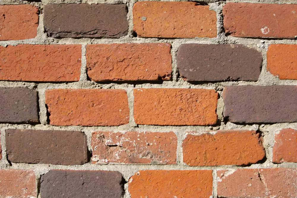 Close-up van een oude handvormsteen gevel met onregelmatige stenen en dunne kalkvoegen