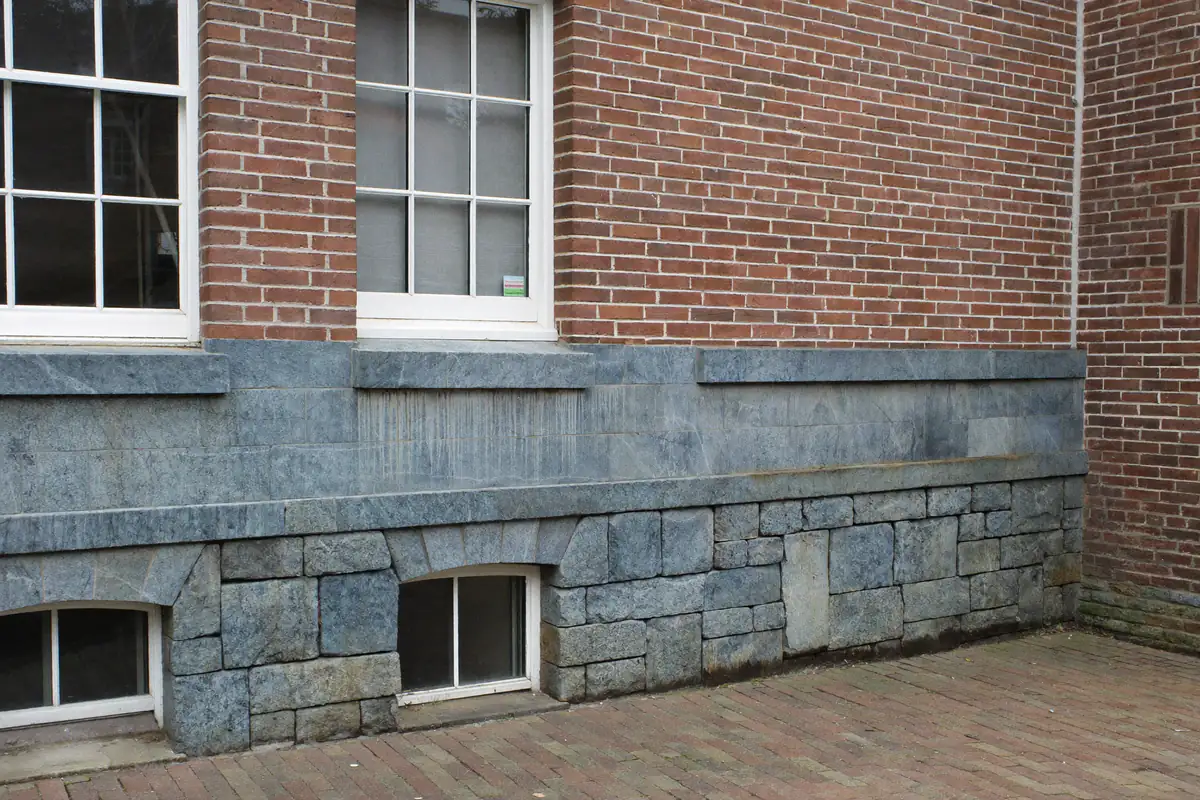 Hardstenen plint en waterslagen onder een rode bakstenen gevel van een oud stadshuis in Zeeland